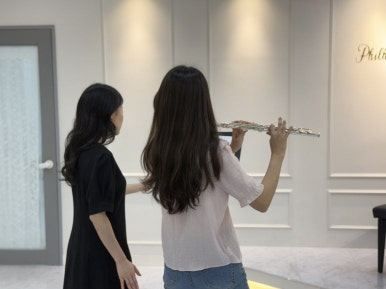 강사가 학생의 플루트 자세를 잡아주는 레슨 장면